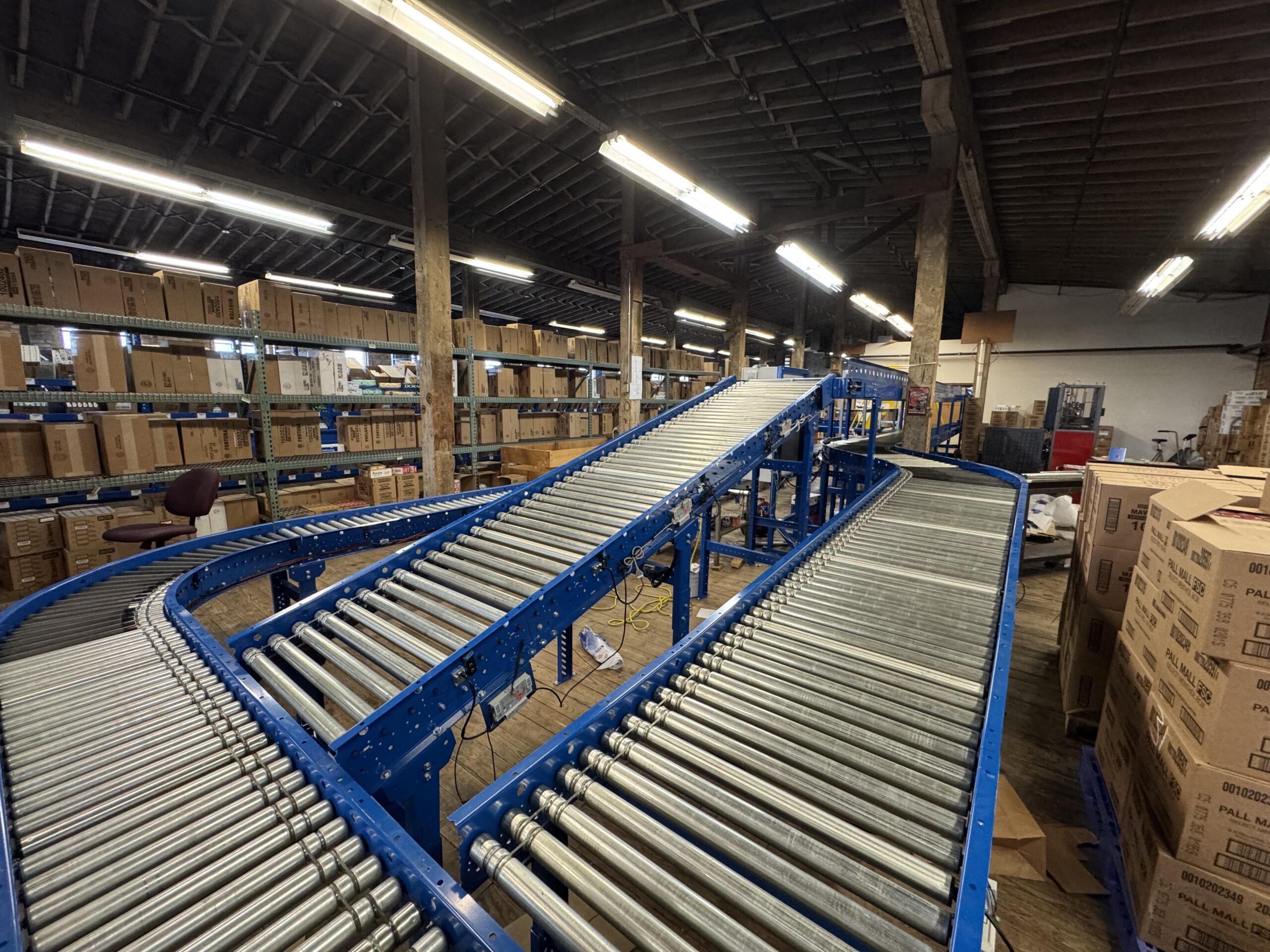 MDR conveyor merge and curve installed in a warehouse with original hardwood floors and brick walls