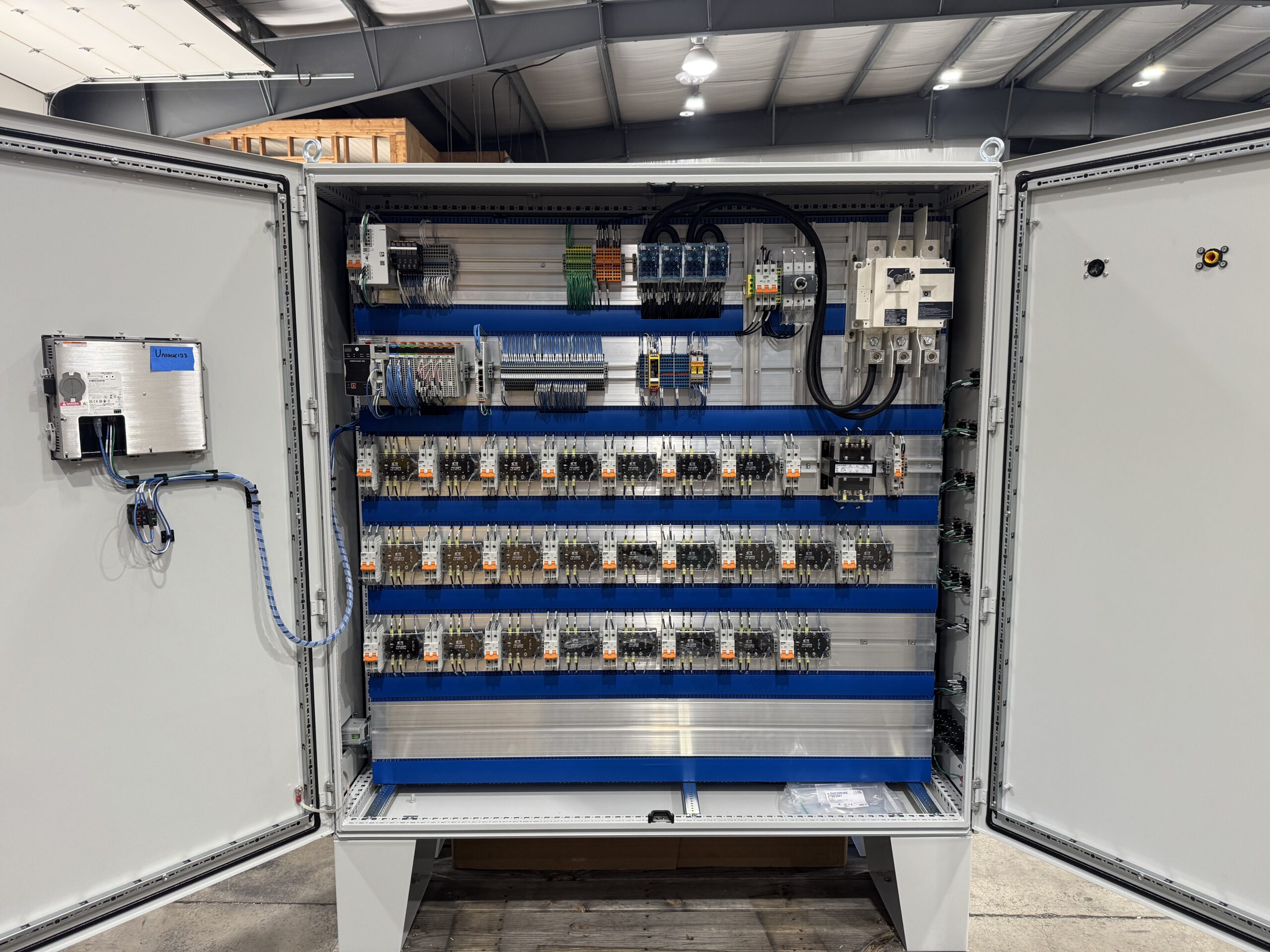 Completed pre-heater control panel open in the CGT shop, showing rows of solid state relays, Allen Bradley PLC, and spring terminal wiring