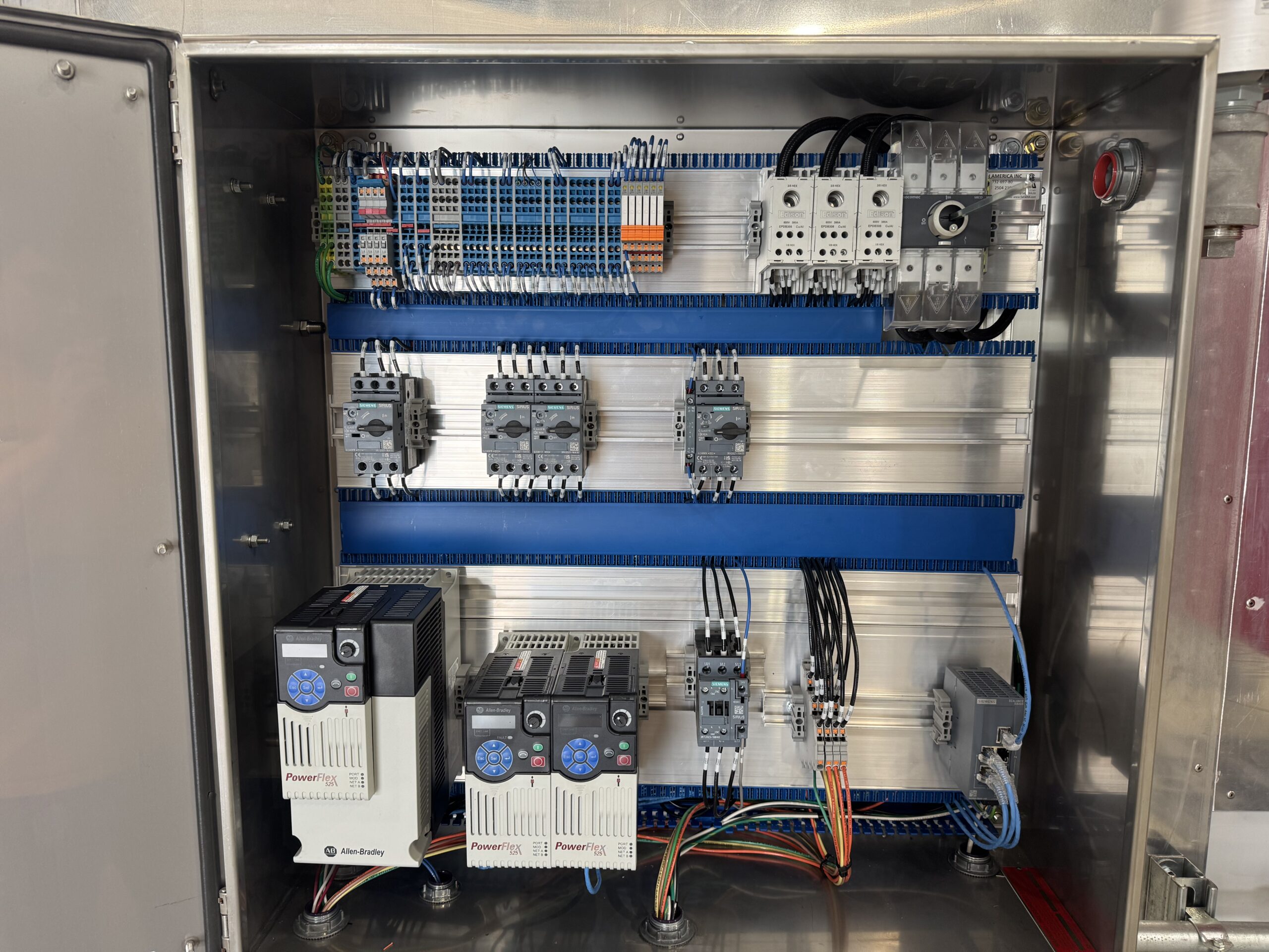 Motor control panel interior showing three Allen-Bradley PowerFlex variable frequency drives, Siemens motor protection circuit breakers, and contactors inside a stainless C1D2 enclosure