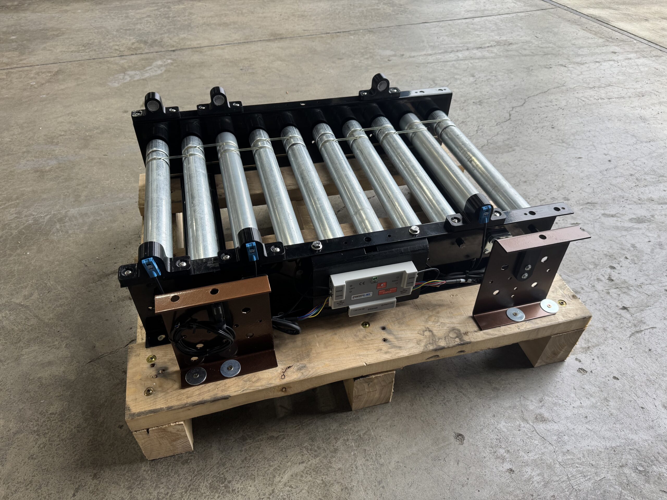 CGT MDR demo unit staged on a wood skid in the shop, showing ConveyLinx-AI2 controller, rollers, photoeyes, and powder-coated side brackets